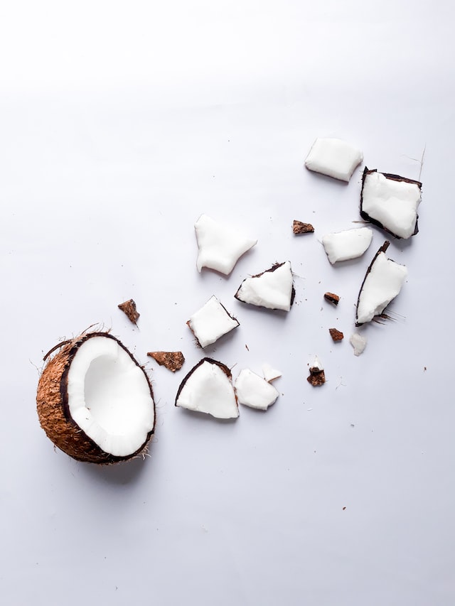 A coconut chopped in half, with one half intact and the other half in fragments