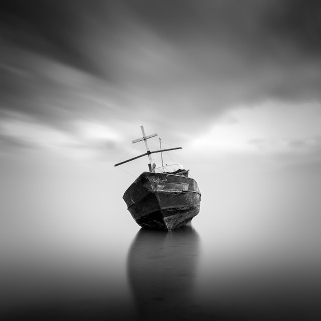 A lurching wooden ship careens dangerously to one side over grey waters